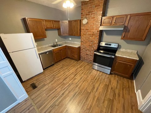 an empty kitchen with wooden floors and a brick wall