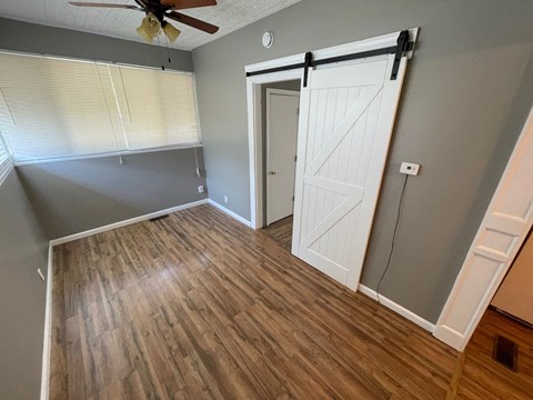 an empty living room with a sliding door to a bedroom