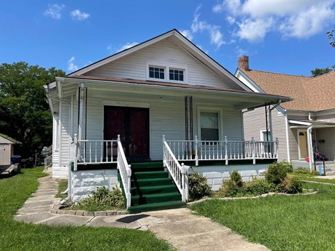 a white house with a porch and green stairs