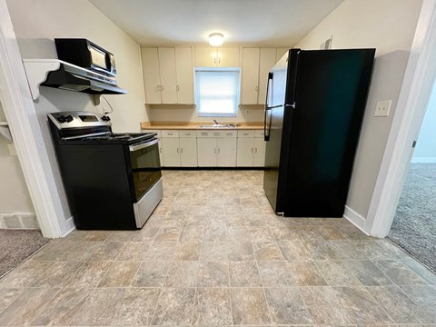 A kitchen with black appliances and white cabinets.