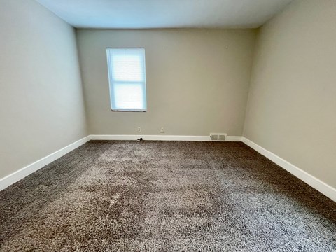 A room with a carpeted floor and a window.