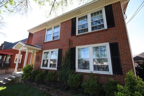 A red brick house with white windows and black shutters.