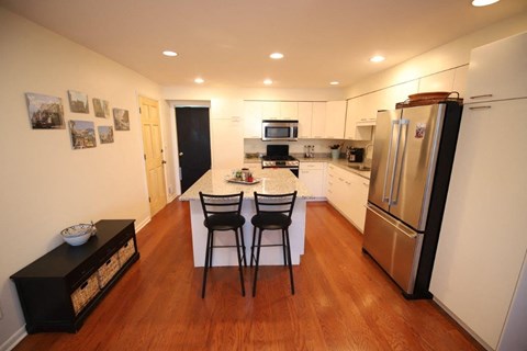 A kitchen with a refrigerator, stove, and table.