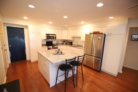 A kitchen with a white counter top and a refrigerator.