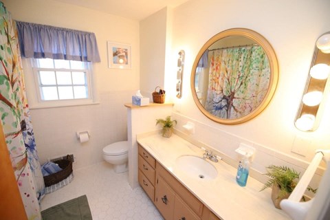 A bathroom with a white counter top and a round mirror.