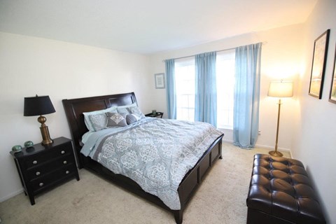 A bedroom with a large bed, a nightstand, and a lamp.