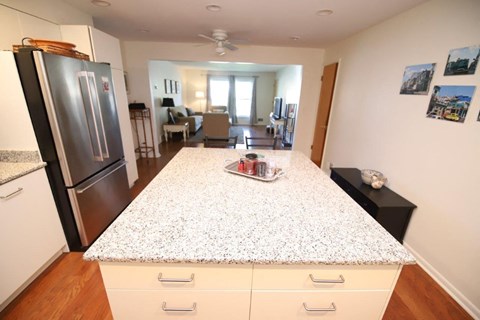A kitchen with a refrigerator, oven, and a dining table with chairs.