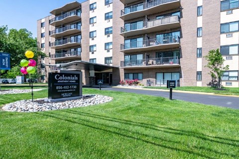 an apartment building with a green lawn and a sign in front of it