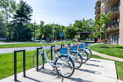 a row of bikes parked in a bike rack outside of an apartment building