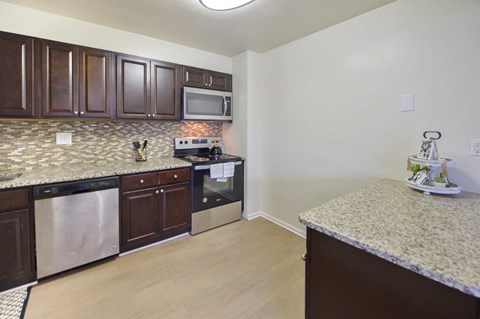 A kitchen with dark brown cabinets and a granite countertop.