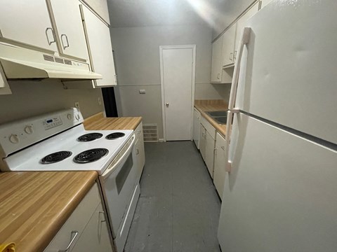 A kitchen with white appliances and wooden countertops.