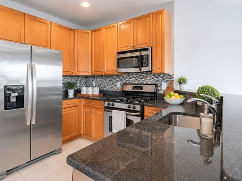 A kitchen with a refrigerator, microwave, oven, and sink.