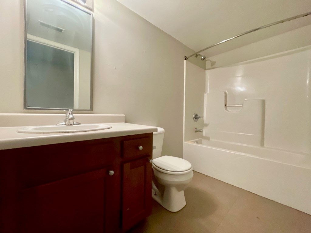 A white toilet sits in a bathroom with a sink and mirror.