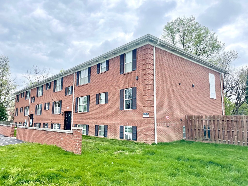 A red brick building with black shutters and a white door.