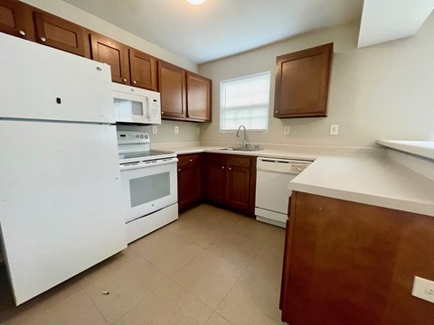 A kitchen with white appliances and brown cabinets.