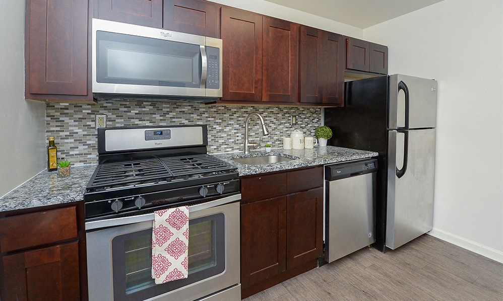 a kitchen with stainless steel appliances and wooden cabinets and a granite counter top