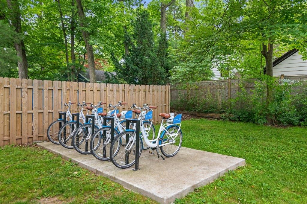 a row of bikes parked on a cement pad next to a fence