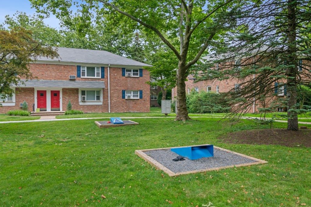 the backyard of a brick house with two trampolines in the grass