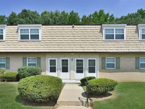 a house with a lawn and bushes in front of it
