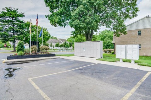 a parking lot with two white boxes in front of a house