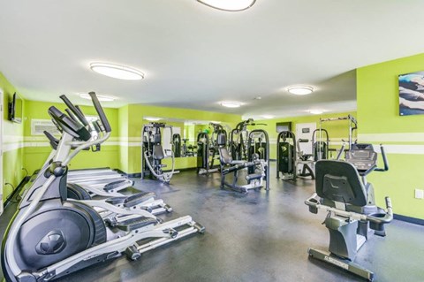 a gym with weights and cardio equipment in a building with green walls