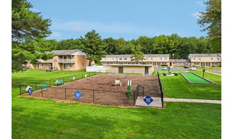 A playground area with a blue sign in the middle of a grassy field.