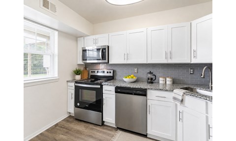 A kitchen with white cabinets and stainless steel appliances.