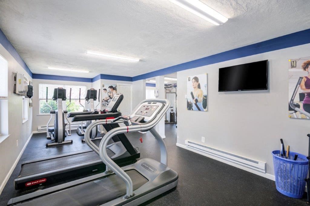 a gym with cardio equipment and a tv on the wall