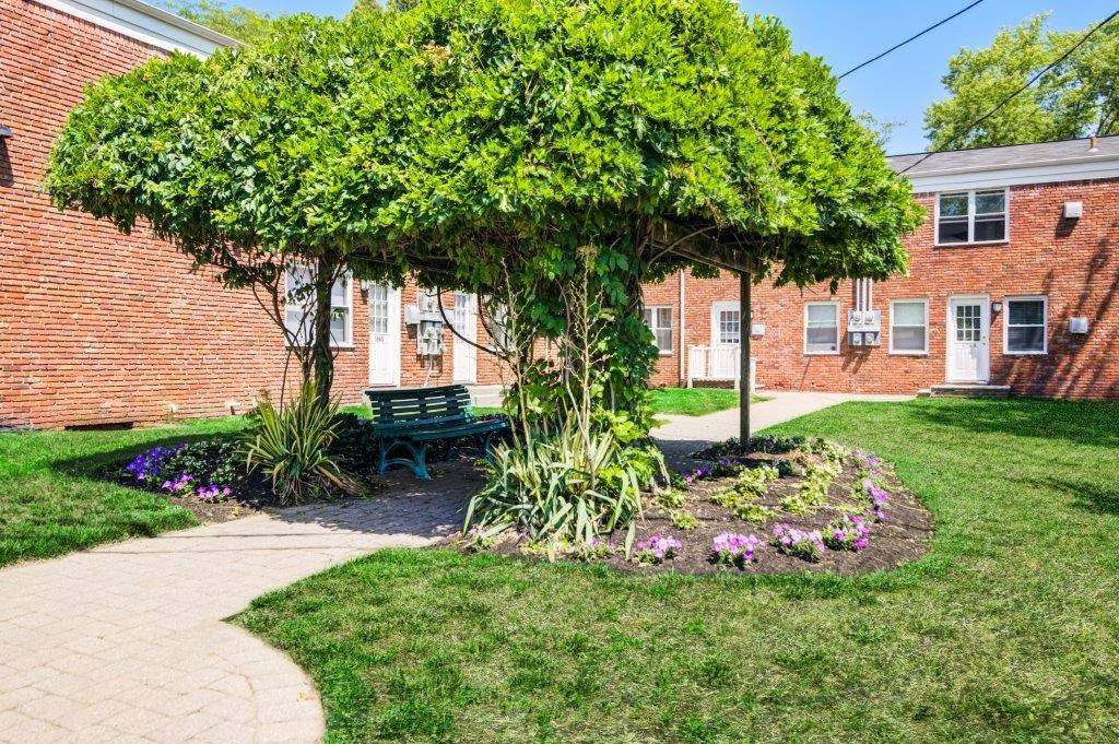 a bench under a tree in front of a brick building