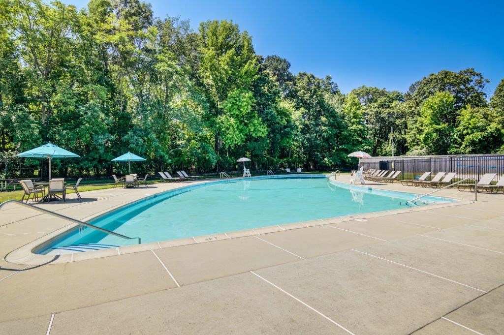 a swimming pool with chairs and umbrellas and trees
