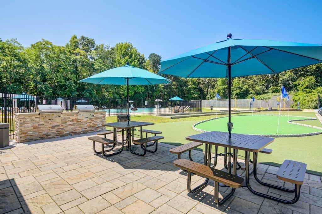 two picnic tables with umbrellas next to a tennis court