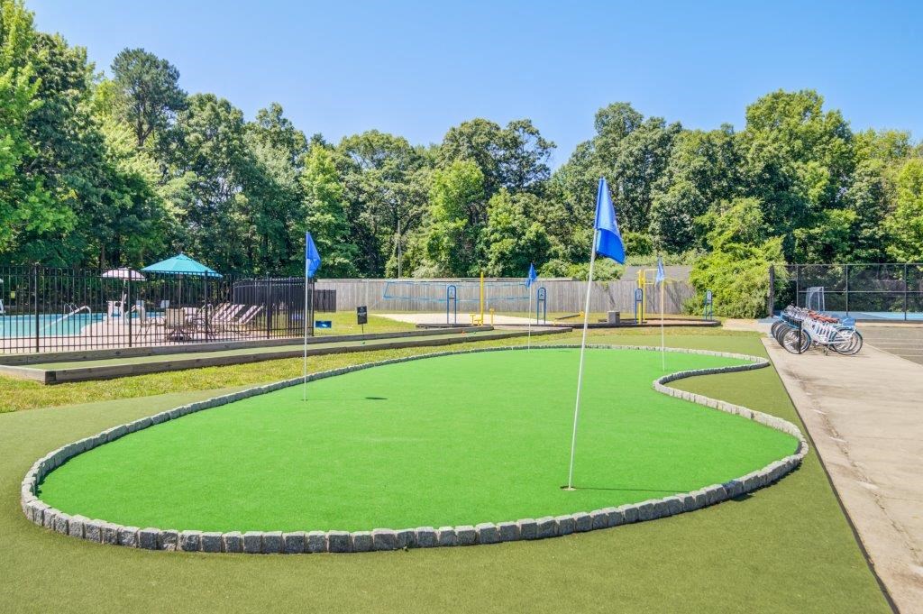 a putting green with blue flags on it and a pool in the background