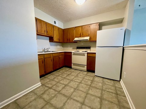 an empty kitchen with white appliances and wooden cabinets