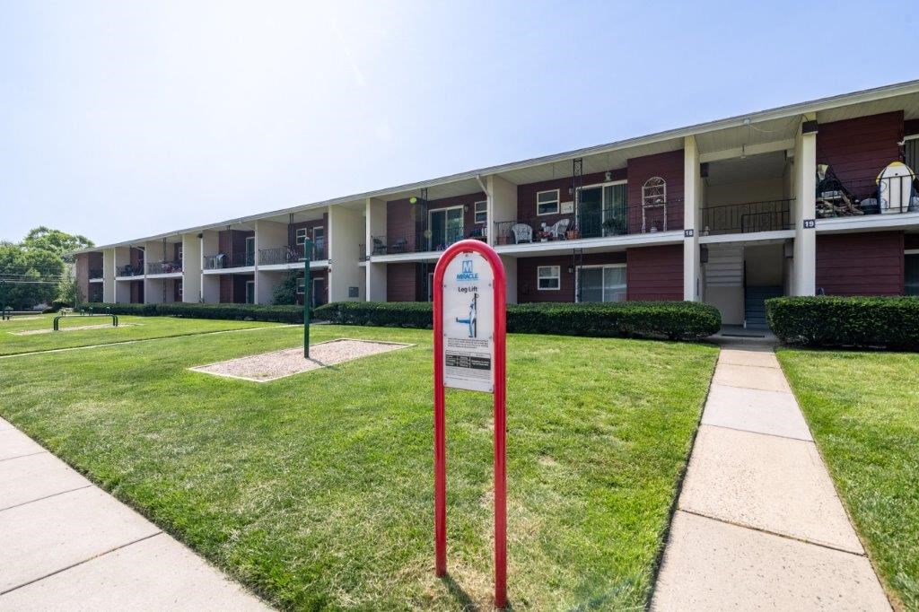 a building with a sidewalk and a sign in the grass