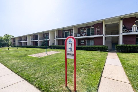 a building with a sidewalk and a sign in the grass
