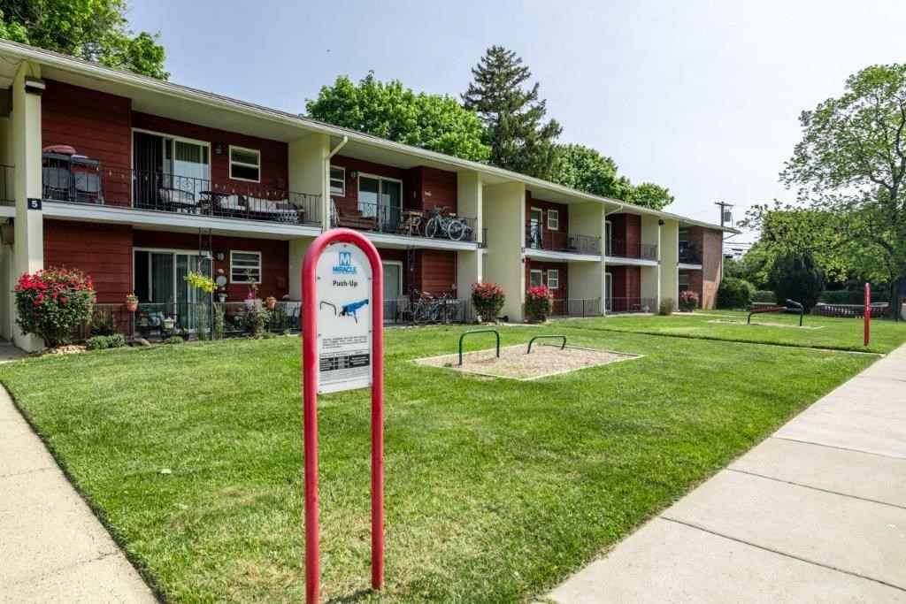 a sign is in the grass in front of an apartment building