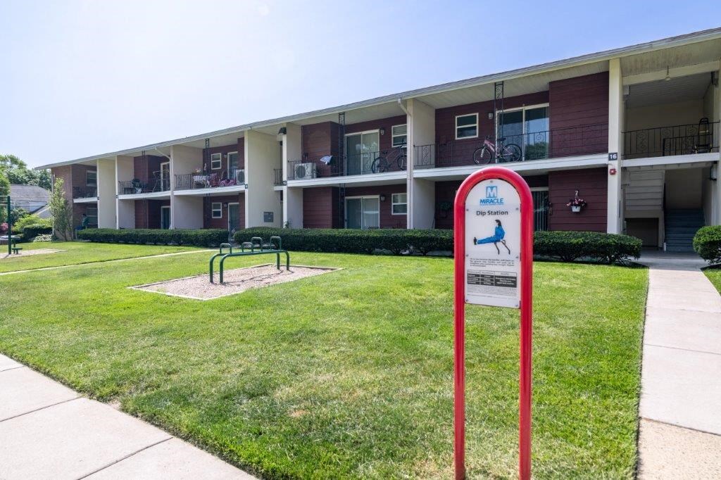 a sign in the grass in front of an apartment building