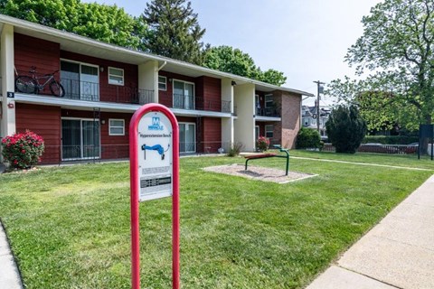 a sign in the grass in front of an apartment building