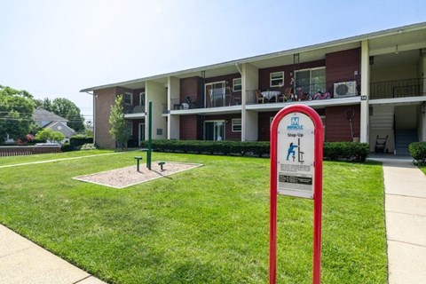 a sign in the grass in front of an apartment building