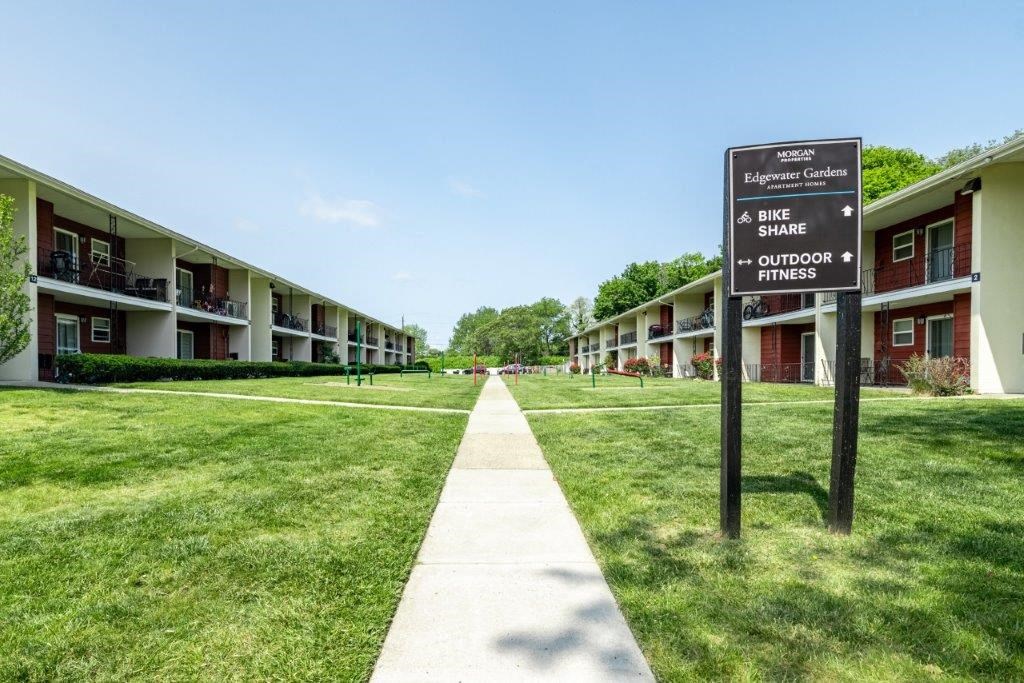 a street sign sitting in the grass in front of some apartments
