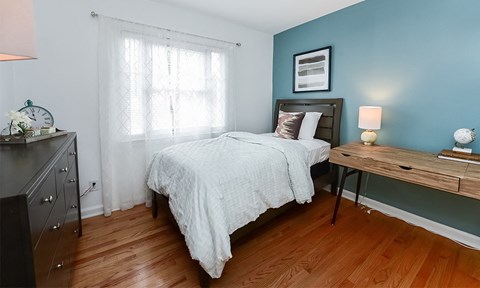 a bedroom with a bed and a desk and a window