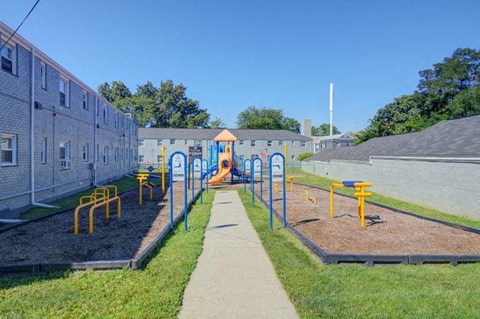 a playground with a sidewalk and yellow and blue playground equipment