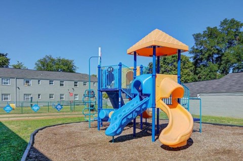 a playground with a blue slide and a yellow umbrella