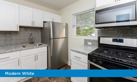 a modern white kitchen with a stainless steel refrigerator and stove