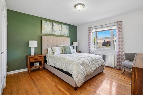 A bedroom with a large bed and a window with curtains.