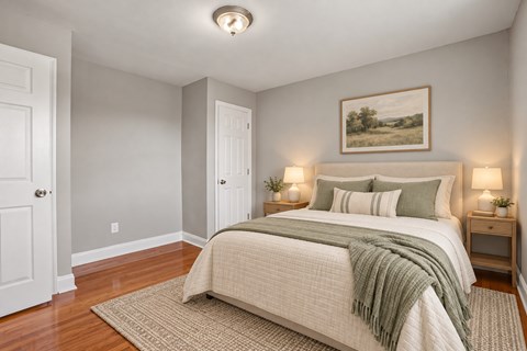 A bedroom with a bed, two nightstands, and a painting on the wall.