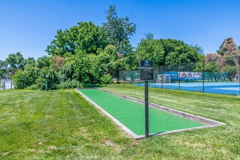 a tennis court with a sign on top of it in a park
