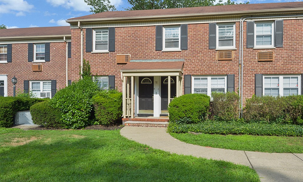 a brick house with a sidewalk in front of it