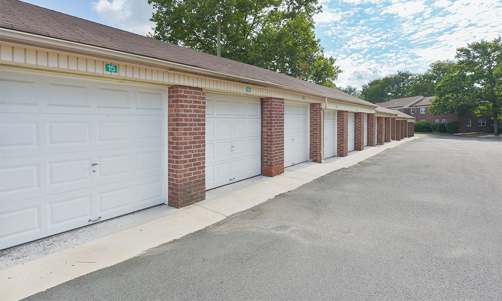 a row of garages with white doors and brick columns