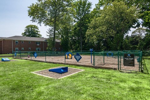 a fenced in dog park with a playground and a building
